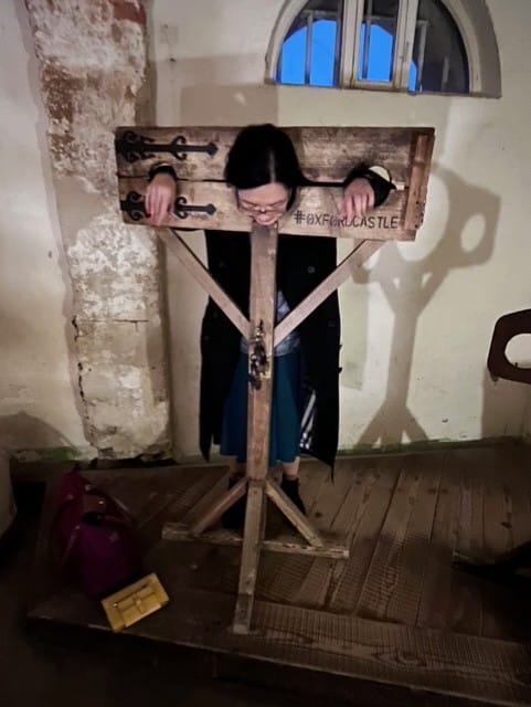 A visitor tries out the stocks at Oxford Castle and Prison